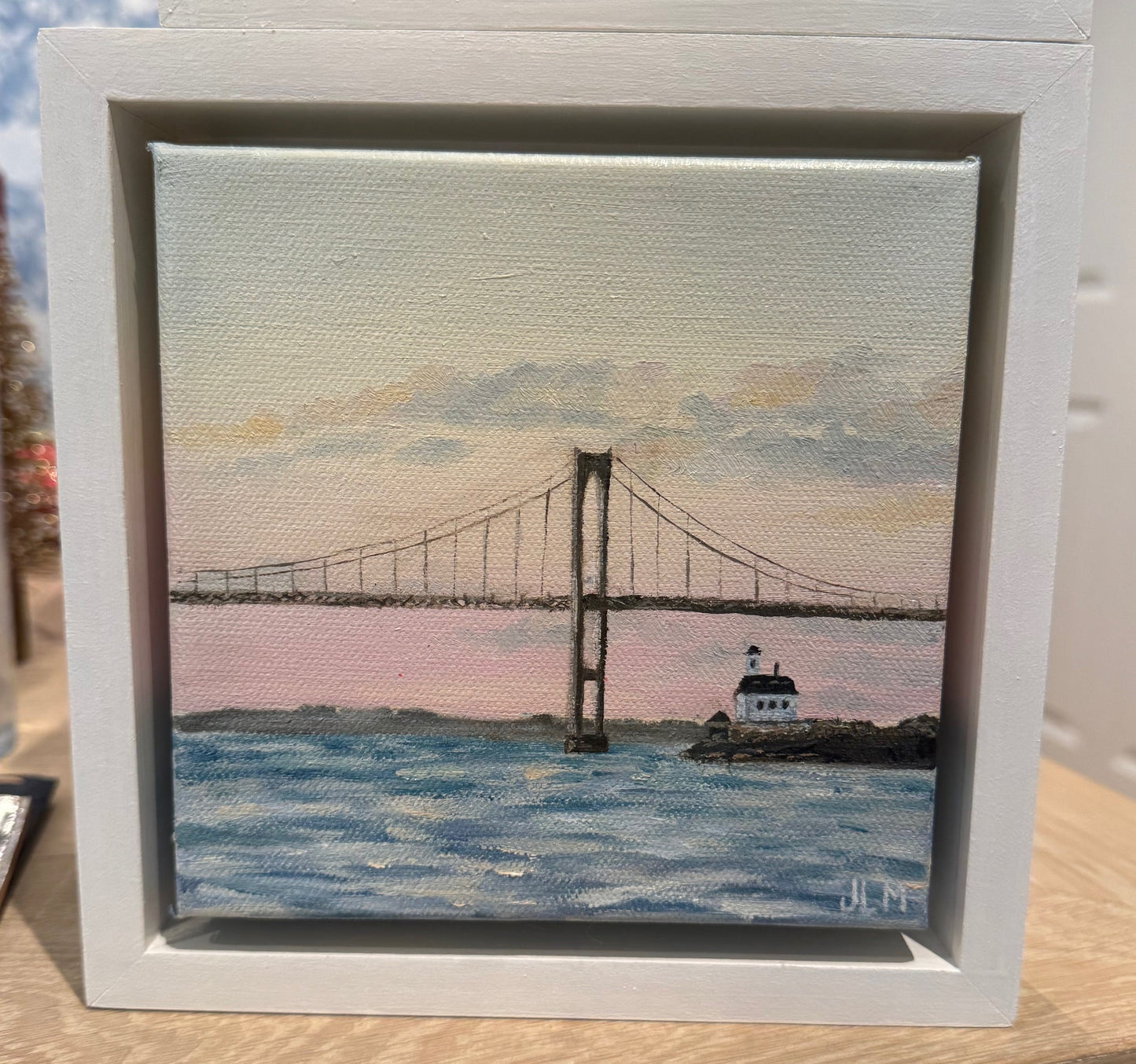 Framed artwork of a lighthouse on a beach and the newport bridge