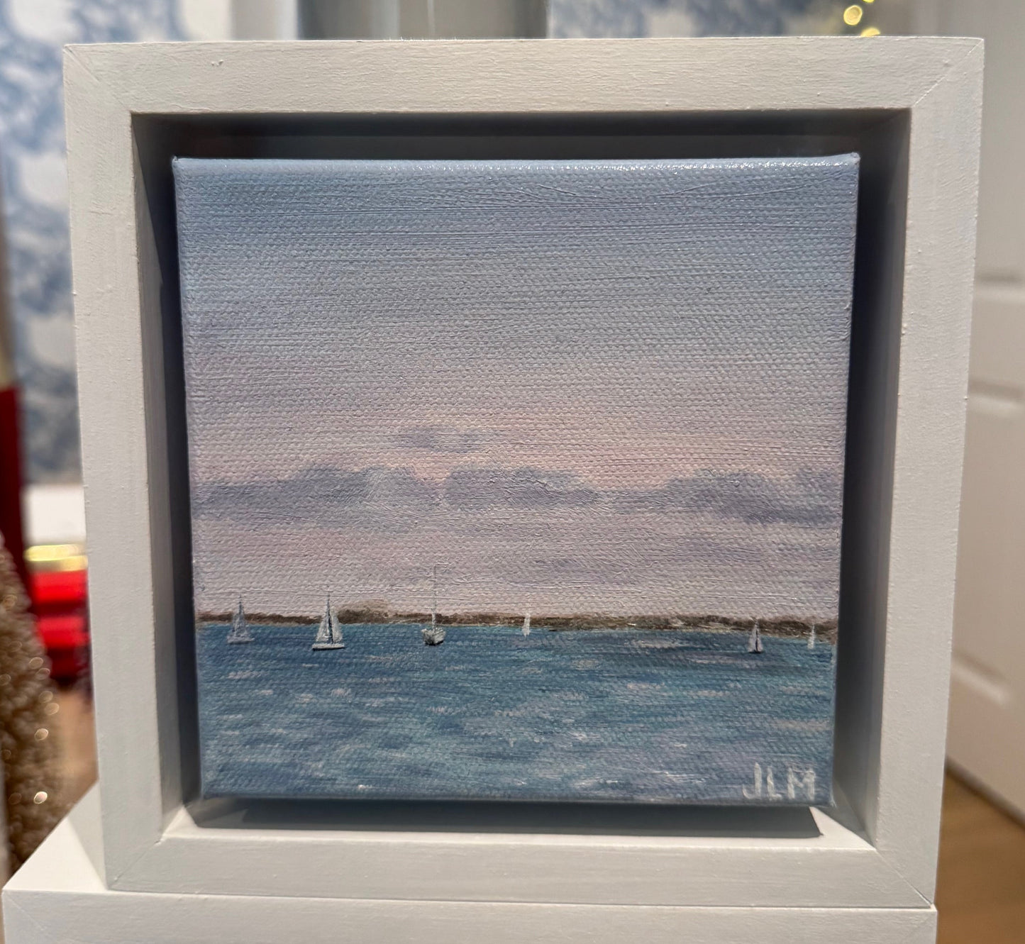 Framed artwork of a landscape with a blue sky and water.